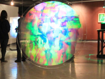 View of the exhibition Interference Coexistence at the HoloCenter Ling Island Cty Clock Tower, circular hologram in front showing abstract field of light by Japanese artist setsuko ishii