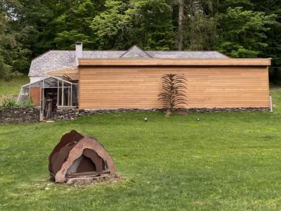 Southwood Holography Laboratories studio in mid-hudson, New York | Image shows a building set in the woods with a lawn and scultpure in the forground